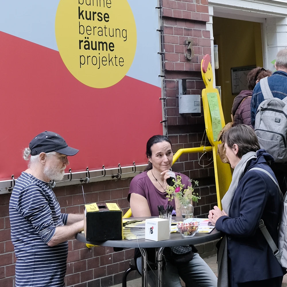 Beratungssituation mit drei Personen vor dem Eingang des B-Treff