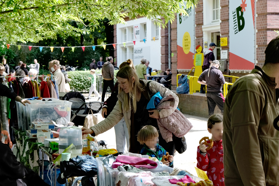 Familien an Flohmarktständen auf dem Außengelände vor dem B Treff